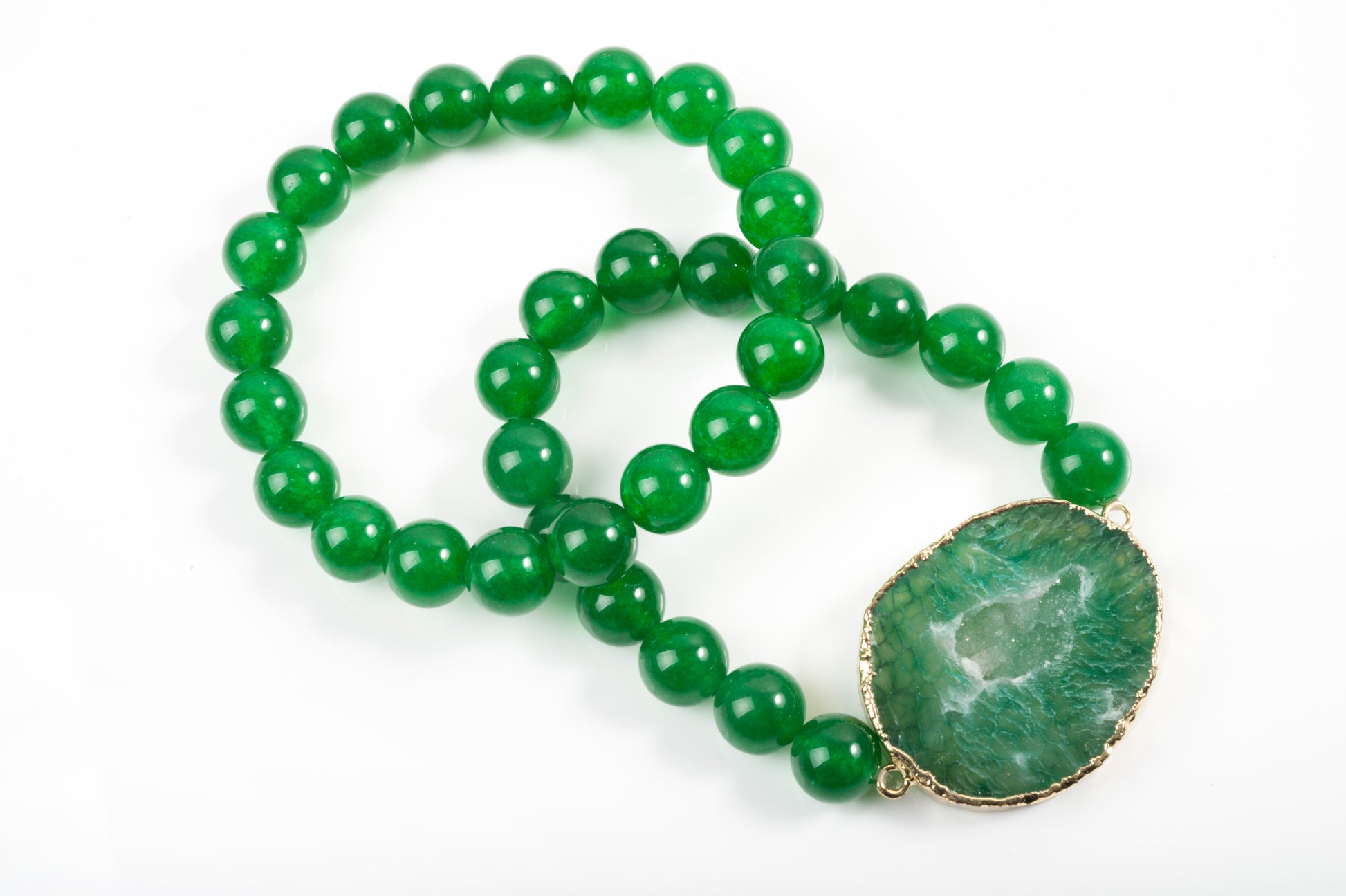 Green beaded necklace with a green stone pendant on a white background